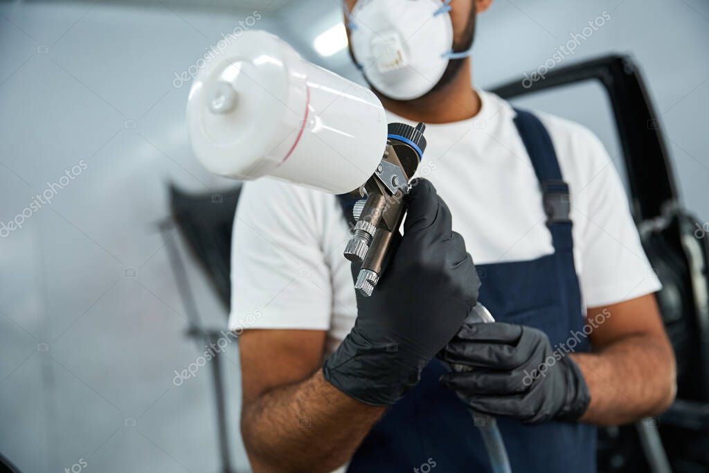 Lackierer trägt mit einer Spritzpistole Autolack auf